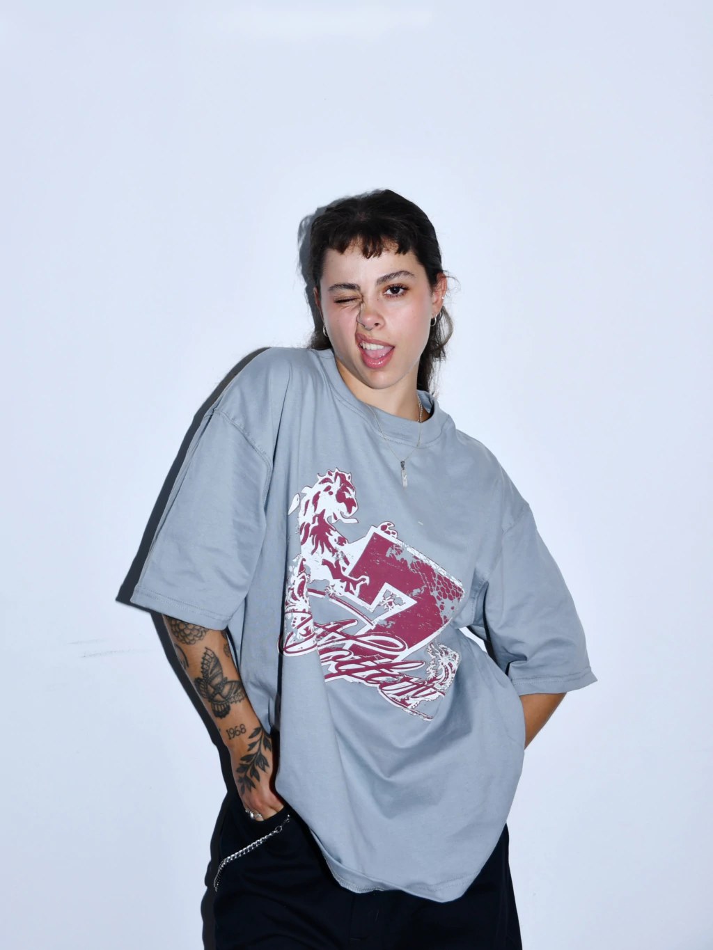Modelo guiñando un ojo con la remera gris estampada en bordó