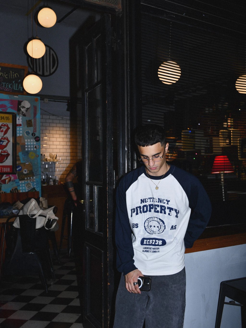 Modelo en la puerta de un bar con la remera azul marino y blanca