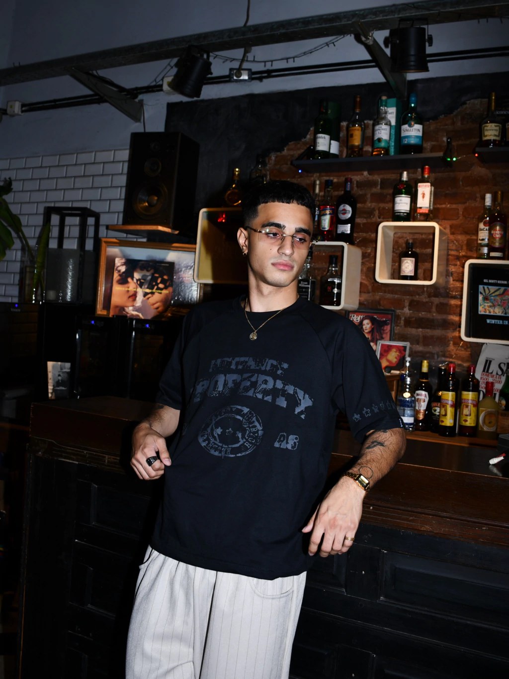 Modelo apoyado en una barra con la remera negra manga corta