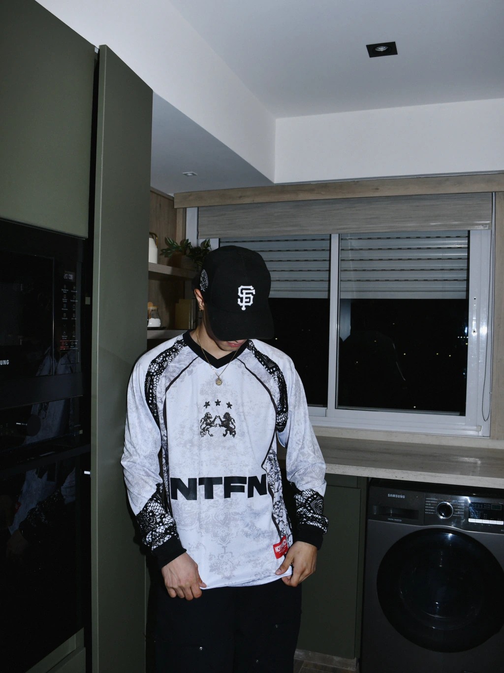 Modelo con gorra sosteniendo el borde de la camiseta Team Notfancy